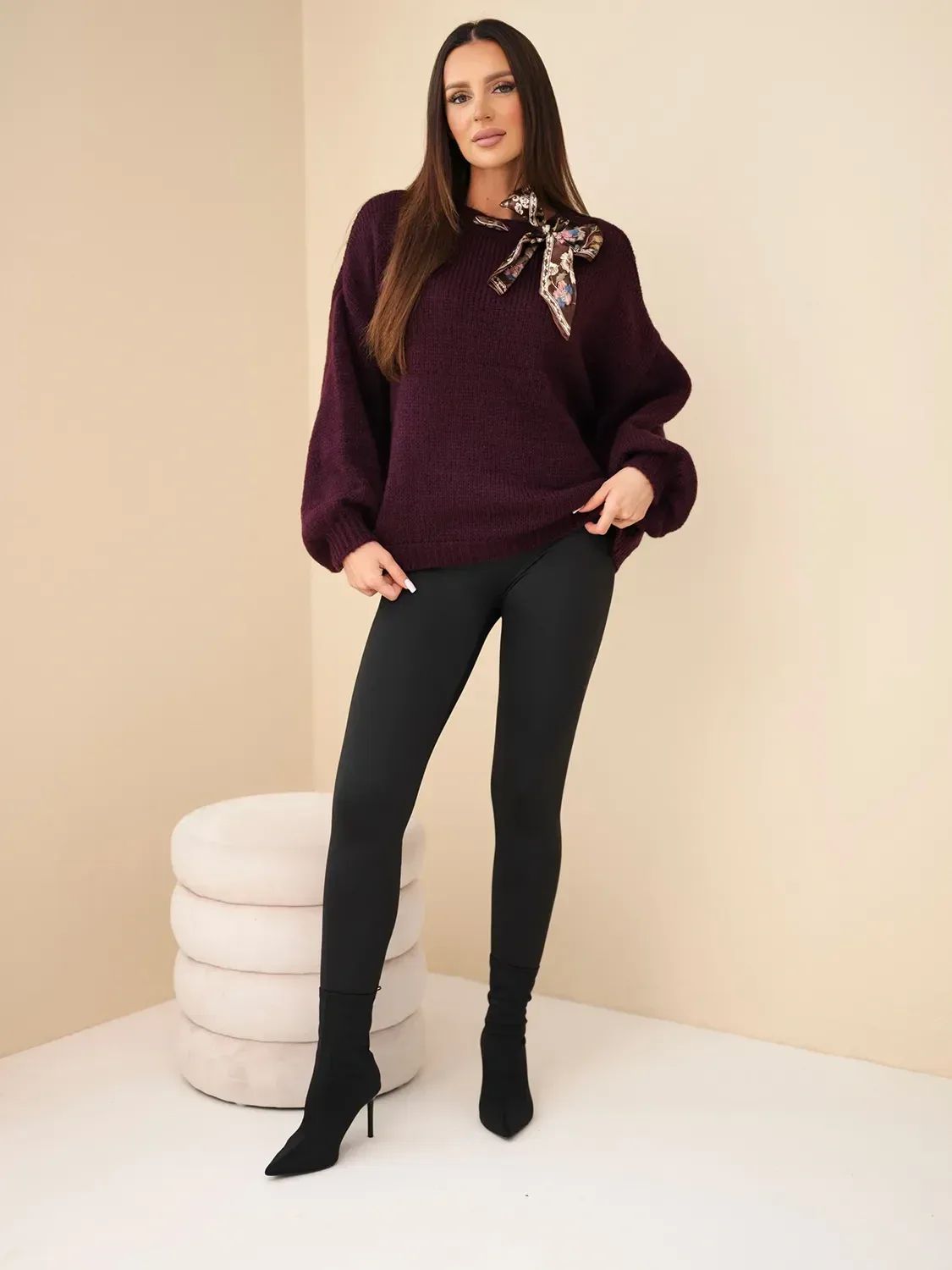 Modelka nosi bordowy sweter z broszką i czarne legginsy Mazii Fashion.