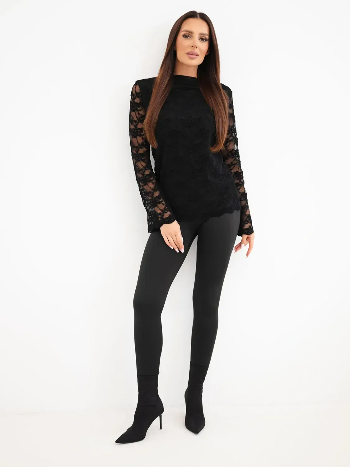 Kobieca modelka w czarnej koronkowej bluzce i czarnych spodniach, stylowy look Mazii Fashion.