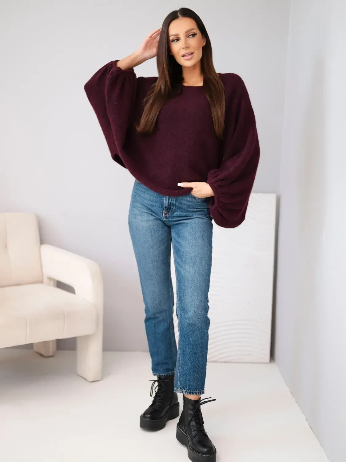 Kobieta w fioletowym swetrze oversize i jeansach, stylowa fotografia modowa.