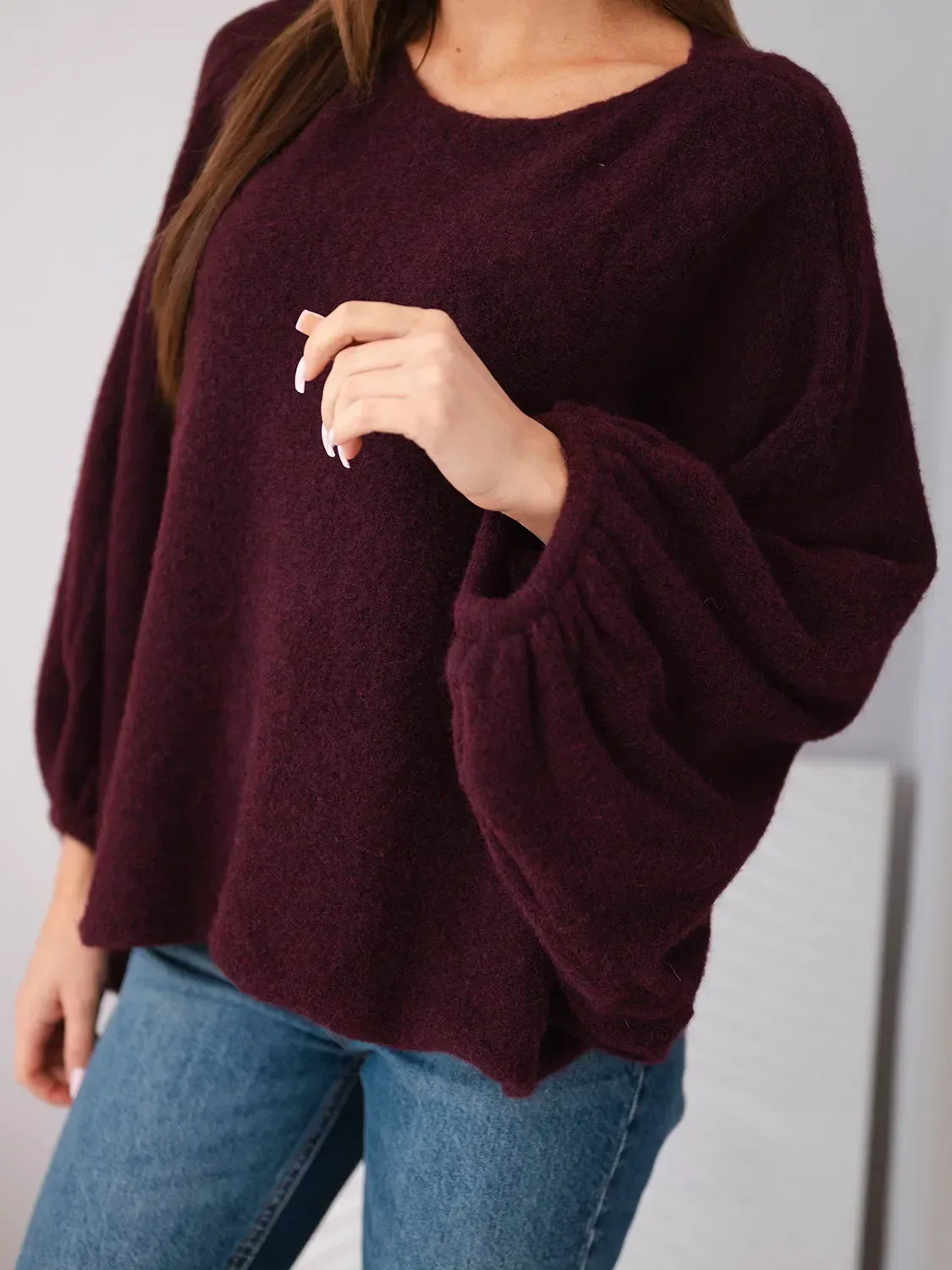 Sweter damski burgundowy o luźnym kroju i bufzkowych rękawach.