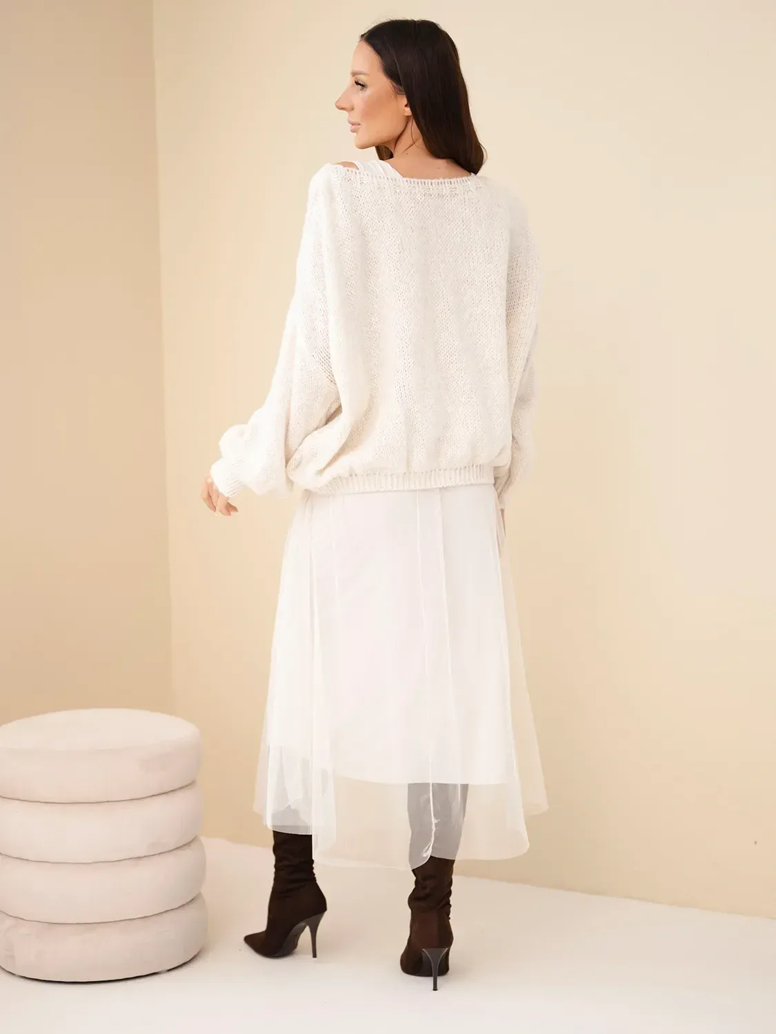 Kobieta w białym miękkim swetrze i białej plisowanej spódnicy, stylowy look Mazii Fashion.